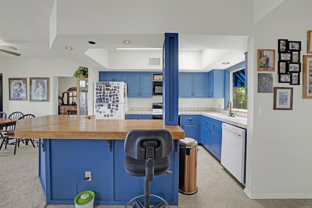 kitchen with a raised ceiling, a kitchen bar, white appliances, and blue cabinets