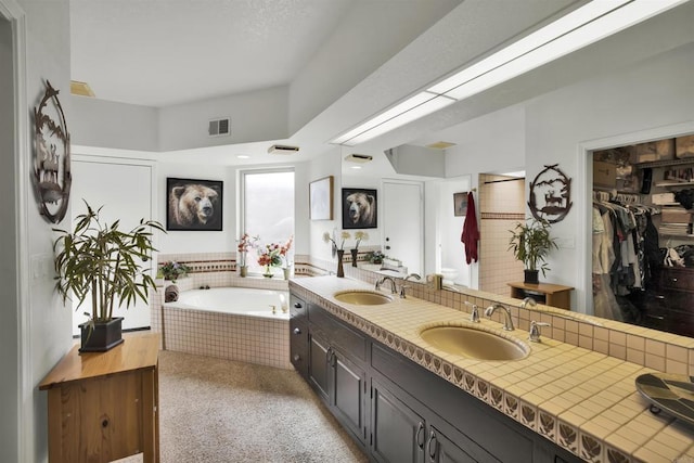 bathroom featuring a relaxing tiled tub and vanity