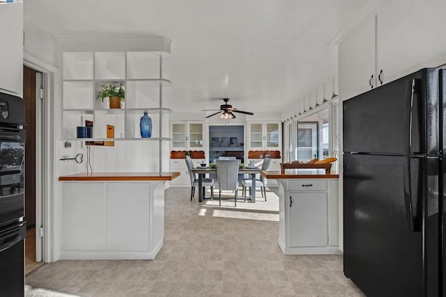 kitchen with black refrigerator, white cabinets, and ceiling fan