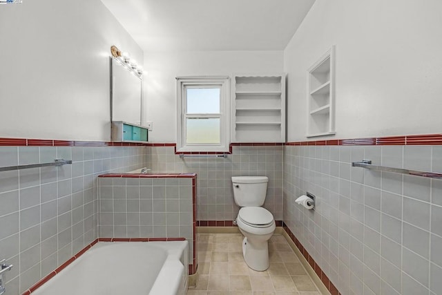 bathroom with tile patterned flooring, toilet, tile walls, and a tub