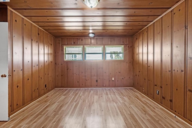 spare room featuring plenty of natural light, wood walls, and light wood-type flooring