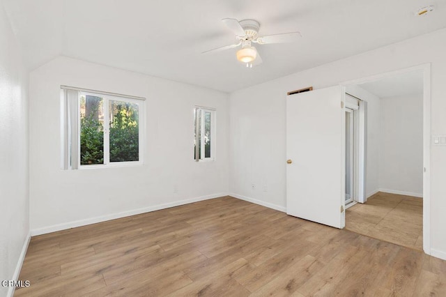 spare room with ceiling fan, vaulted ceiling, and light wood-type flooring