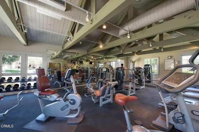 workout area with high vaulted ceiling and rail lighting