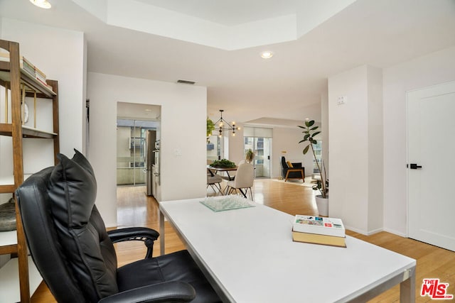 office featuring light hardwood / wood-style floors and a notable chandelier