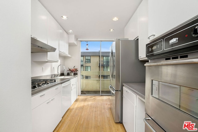 kitchen with exhaust hood, white cabinets, sink, light hardwood / wood-style floors, and stainless steel appliances