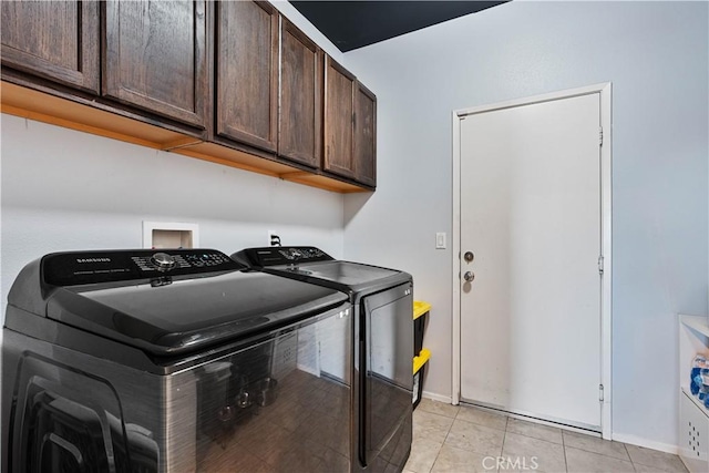 washroom with cabinets, light tile patterned floors, and washing machine and clothes dryer