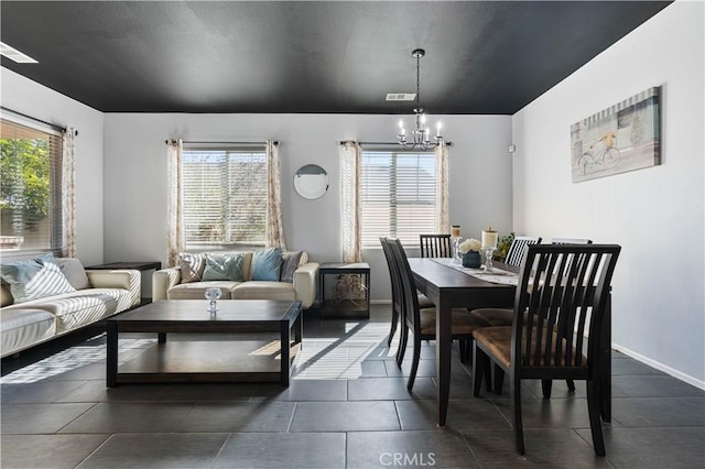 dining room with dark tile patterned floors and a chandelier