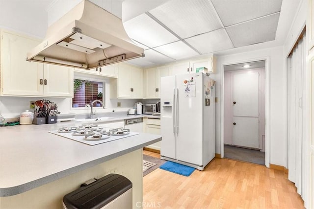 kitchen featuring kitchen peninsula, white appliances, island range hood, and white cabinetry