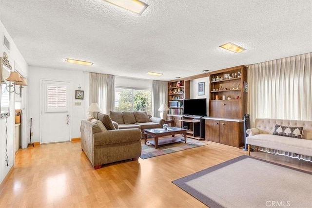 living room with a textured ceiling and light wood-type flooring