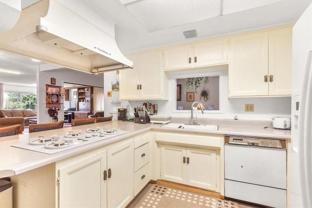 kitchen with kitchen peninsula, white appliances, ventilation hood, sink, and cream cabinets