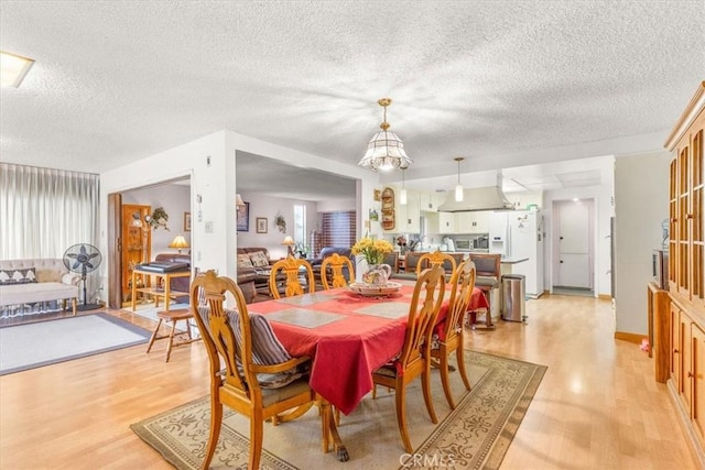 dining room featuring a chandelier, a textured ceiling, light hardwood / wood-style flooring, and a healthy amount of sunlight