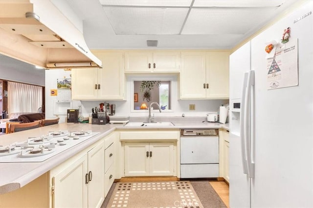 kitchen with cream cabinets, sink, extractor fan, and white appliances