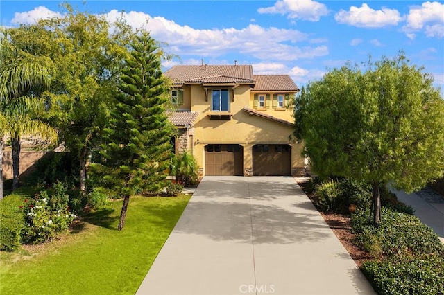 mediterranean / spanish home featuring a garage and a front lawn