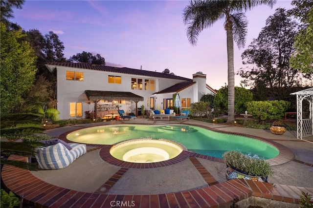 exterior space featuring a swimming pool with hot tub and a patio area