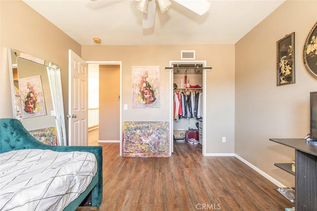 bedroom with ceiling fan, a spacious closet, dark wood-type flooring, and a closet