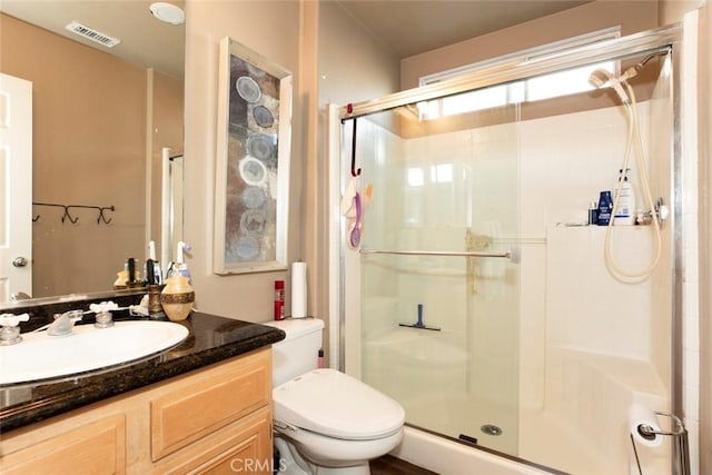 bathroom featuring vanity, toilet, and a shower with shower door