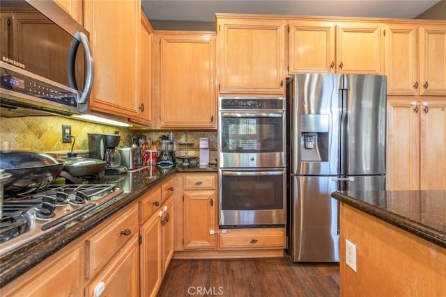 kitchen featuring dark hardwood / wood-style flooring, stainless steel appliances, tasteful backsplash, and dark stone counters