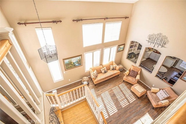 living room with a chandelier, a towering ceiling, hardwood / wood-style flooring, and a healthy amount of sunlight