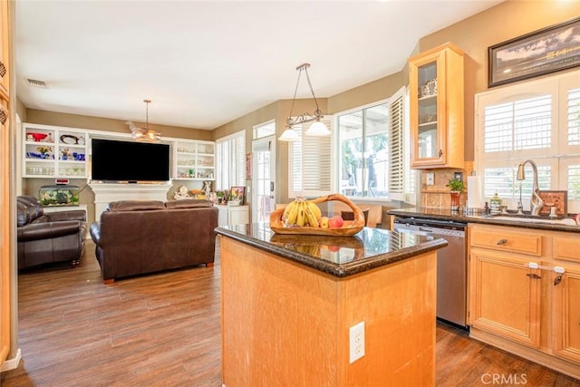 kitchen featuring dark stone counters, sink, wood-type flooring, dishwasher, and a kitchen island