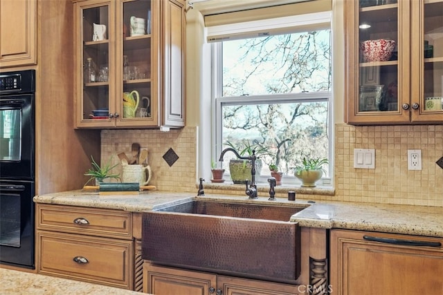 kitchen featuring light stone counters, sink, decorative backsplash, and double oven