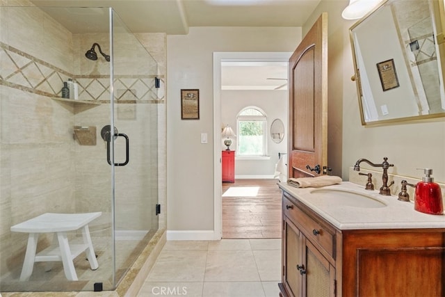 bathroom with a shower with shower door, vanity, and tile patterned flooring