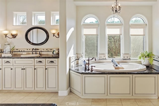 bathroom featuring sink, a washtub, an inviting chandelier, and tile patterned flooring