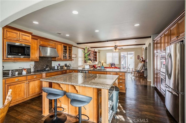 kitchen with a kitchen breakfast bar, stainless steel appliances, sink, dark hardwood / wood-style floors, and a kitchen island