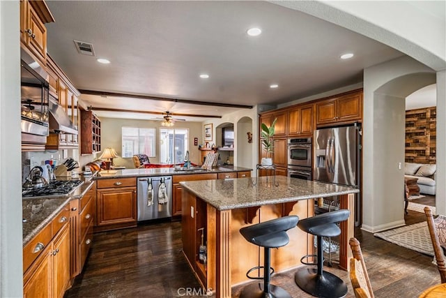 kitchen with kitchen peninsula, appliances with stainless steel finishes, dark wood-type flooring, sink, and a center island