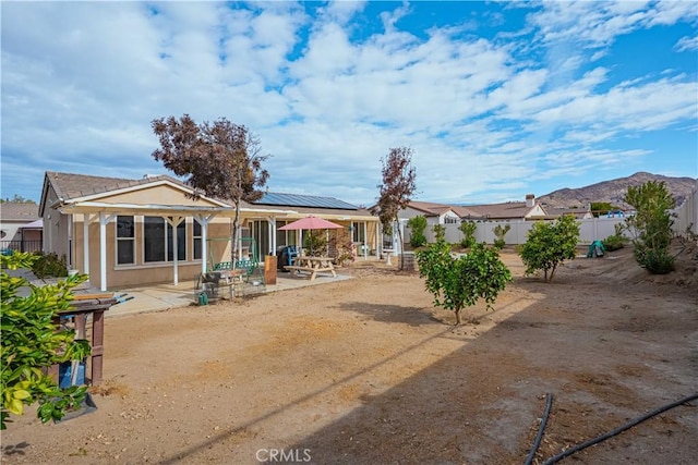 rear view of house with a mountain view, a patio, and solar panels