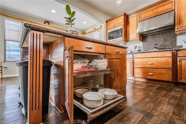 kitchen with dark hardwood / wood-style flooring, built in microwave, and exhaust hood