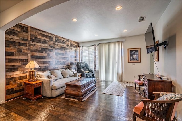 living room featuring dark wood-type flooring and wood walls