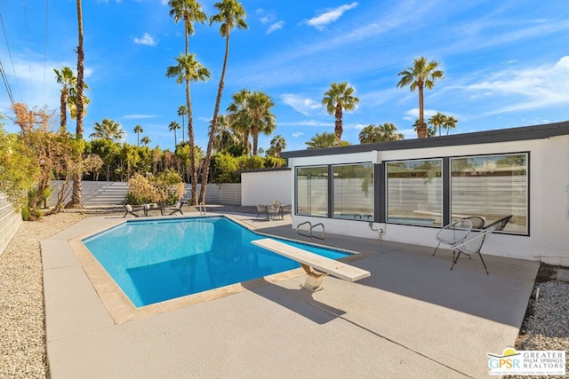 view of swimming pool with a diving board and a patio