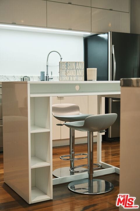 bar with black fridge and hardwood / wood-style floors