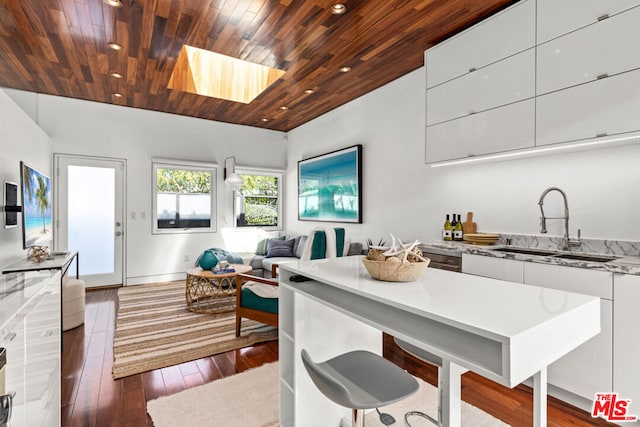 kitchen with a skylight, sink, wooden ceiling, dark hardwood / wood-style floors, and white cabinets