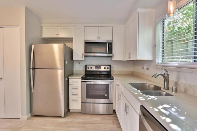 kitchen featuring white cabinetry, sink, stainless steel appliances, and light stone counters