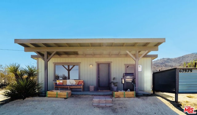 doorway to property with a mountain view and a porch