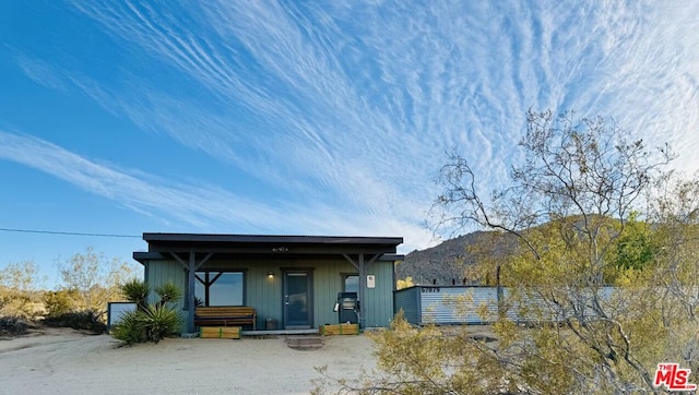 back of property with a mountain view and a porch