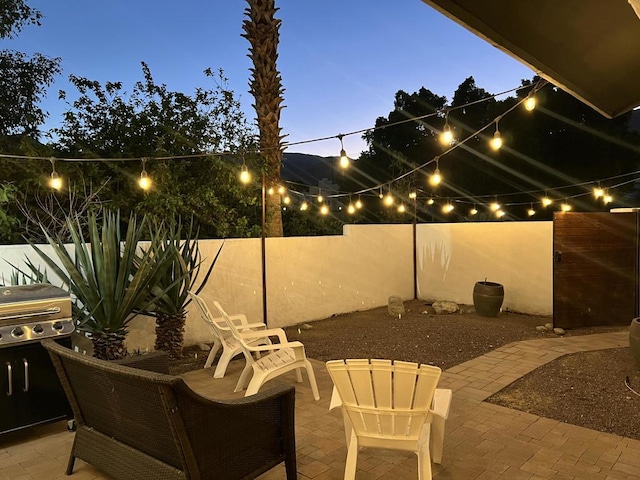 patio terrace at dusk featuring area for grilling