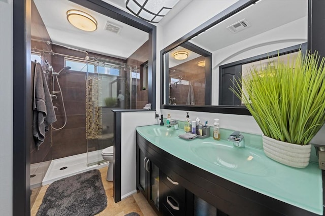 bathroom featuring vanity, toilet, and tiled shower