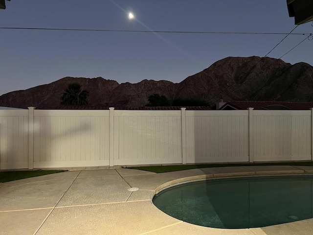 pool at dusk featuring a mountain view