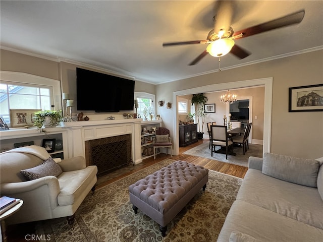 living room featuring hardwood / wood-style floors, ceiling fan with notable chandelier, and ornamental molding