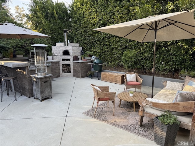 view of patio / terrace featuring an outdoor living space with a fireplace, an outdoor bar, and grilling area