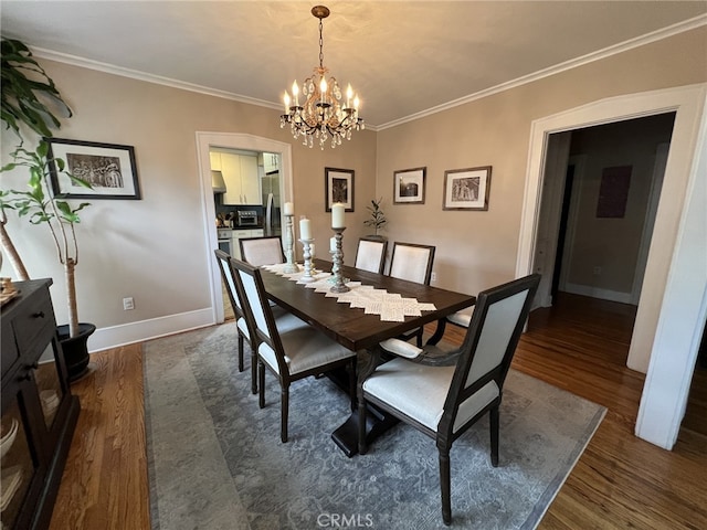 dining room featuring a notable chandelier, ornamental molding, and dark wood-type flooring