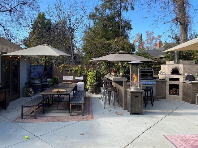 view of patio with an outdoor stone fireplace, exterior bar, grilling area, and an outdoor kitchen