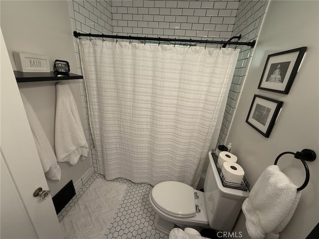 bathroom featuring a shower with shower curtain, tile patterned flooring, and toilet