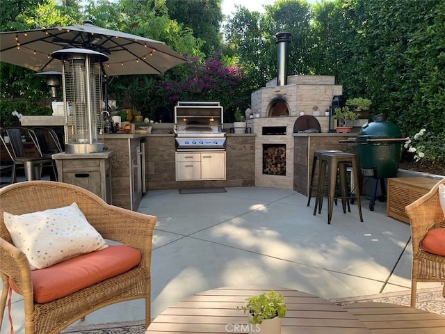 view of patio with area for grilling, an outdoor bar, an outdoor fireplace, and grilling area