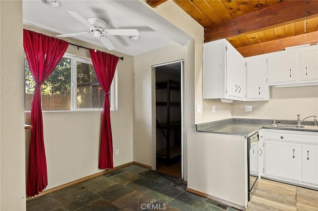 kitchen with beam ceiling, a sink, white cabinetry, and dishwashing machine