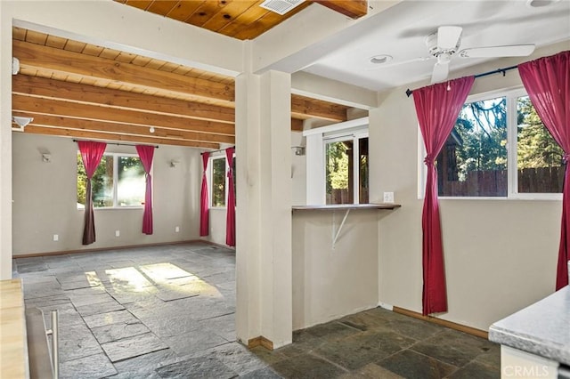 interior space with beamed ceiling, stone tile floors, a ceiling fan, wood ceiling, and baseboards