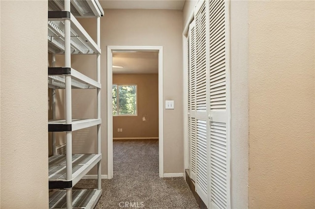 hallway featuring carpet flooring and baseboards
