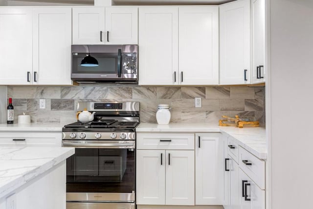 kitchen with appliances with stainless steel finishes, decorative backsplash, white cabinets, and light stone counters